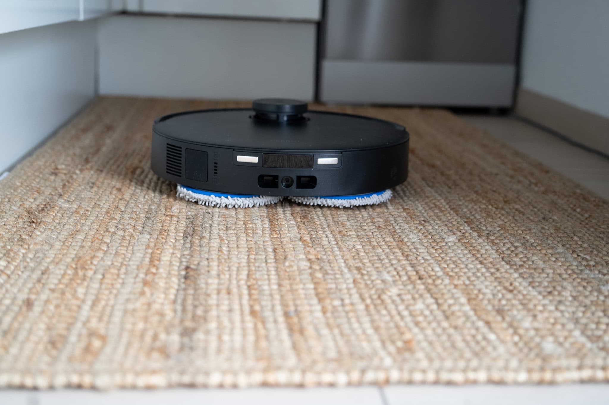 Staubsaugroboter auf einem Teppich, smartes Reinigungsgerät, automatisierte Haushaltshelfer, robotische Saugmaschine, effiziente Bodenreinigung, moderne Haustechnik.