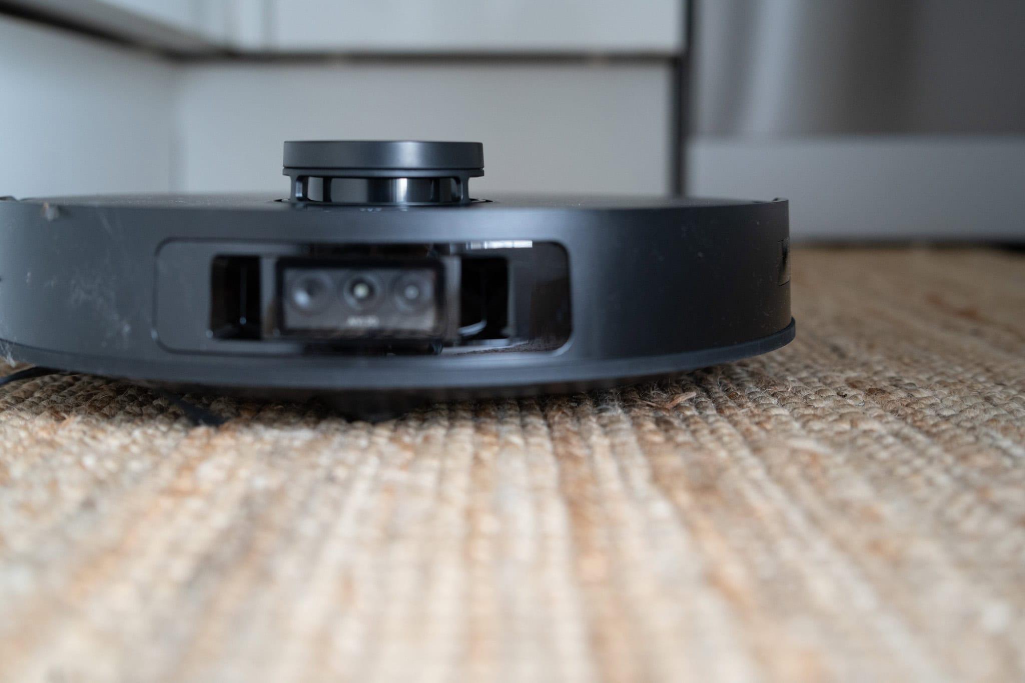 Saugroboter auf einem Teppichboden, modern und schwarz, erleichtert die Hausarbeit durch intelligente Steuerung und automatische Reinigung.