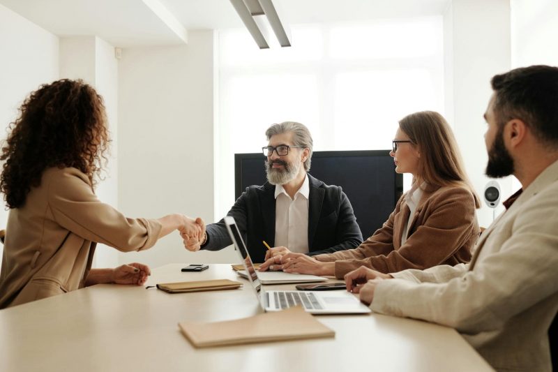 Handschlag bei Geschäftsbesprechung in moderner Büroumgebung, Teamarbeit, Erfolg und Zusammenarbeit, professionelle Diskussion, Technik, Innovation, Geschäftsmeeting, Teamwork, modernes Büro, Erfolg.