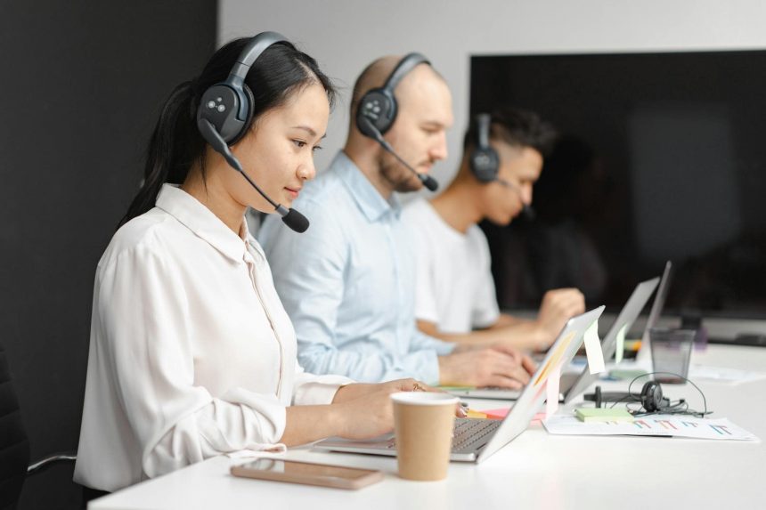Erfahrene Call-Center-Mitarbeiter bei der Arbeit mit Headsets und Laptops, um Kundenanfragen im Bereich Smart Home, Hardware und Streaming effizient zu bearbeiten. Fachkräfte im technischen Support.