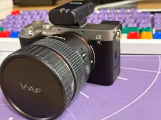 Hochwertige Sony Alpha Kamera mit wechselbarem Objektiv für professionelles Fotografieren, auf einem kreativen Arbeitsplatz mit Tastatur im Hintergrund.