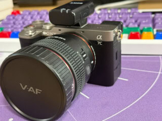 Hochwertige Sony Alpha Kamera mit wechselbarem Objektiv für professionelles Fotografieren, auf einem kreativen Arbeitsplatz mit Tastatur im Hintergrund.