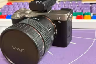 Hochwertige Sony Alpha Kamera mit wechselbarem Objektiv für professionelles Fotografieren, auf einem kreativen Arbeitsplatz mit Tastatur im Hintergrund.