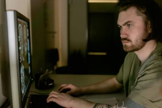 Hochwertiges Bild eines jungen Mannes, der konzentriert an seinem Computer arbeitet, um Film- oder Serien-Streaming-Daten zu analysieren, im Smart Home Umfeld.