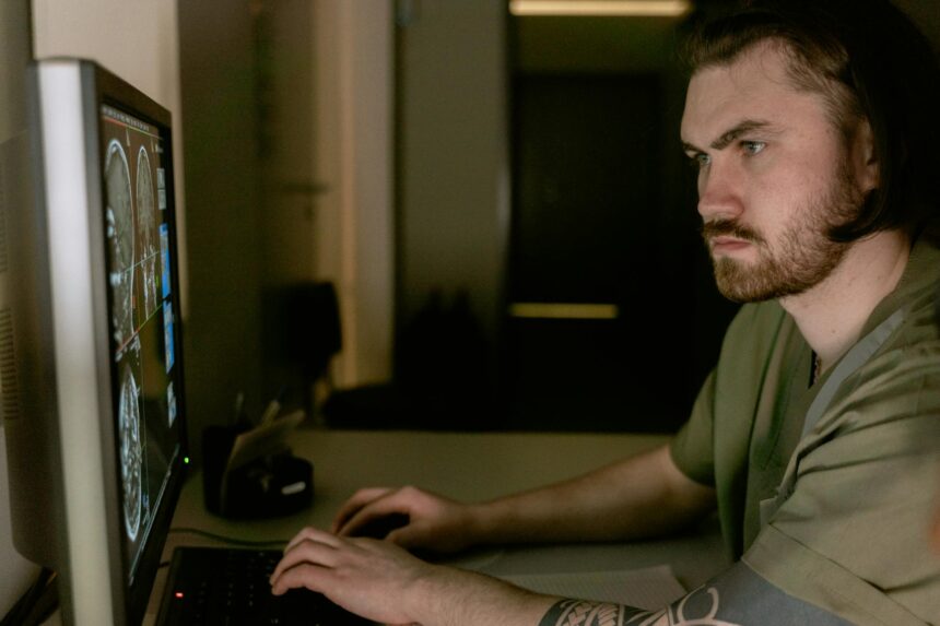 Hochwertiges Bild eines jungen Mannes, der konzentriert an seinem Computer arbeitet, um Film- oder Serien-Streaming-Daten zu analysieren, im Smart Home Umfeld.