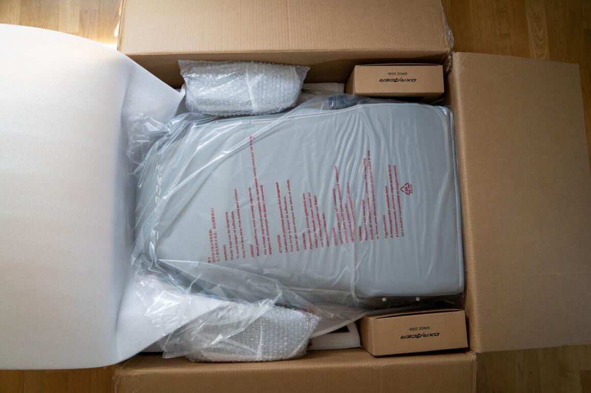 Aufgerissener DXRacer-Karton im Wohnzimmer mit Schaumstoff-Verpackung beim Auspacken