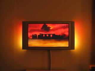 Fernseher mit Ambilight-artigem Hintergrundlicht im abgedunkelten Raum