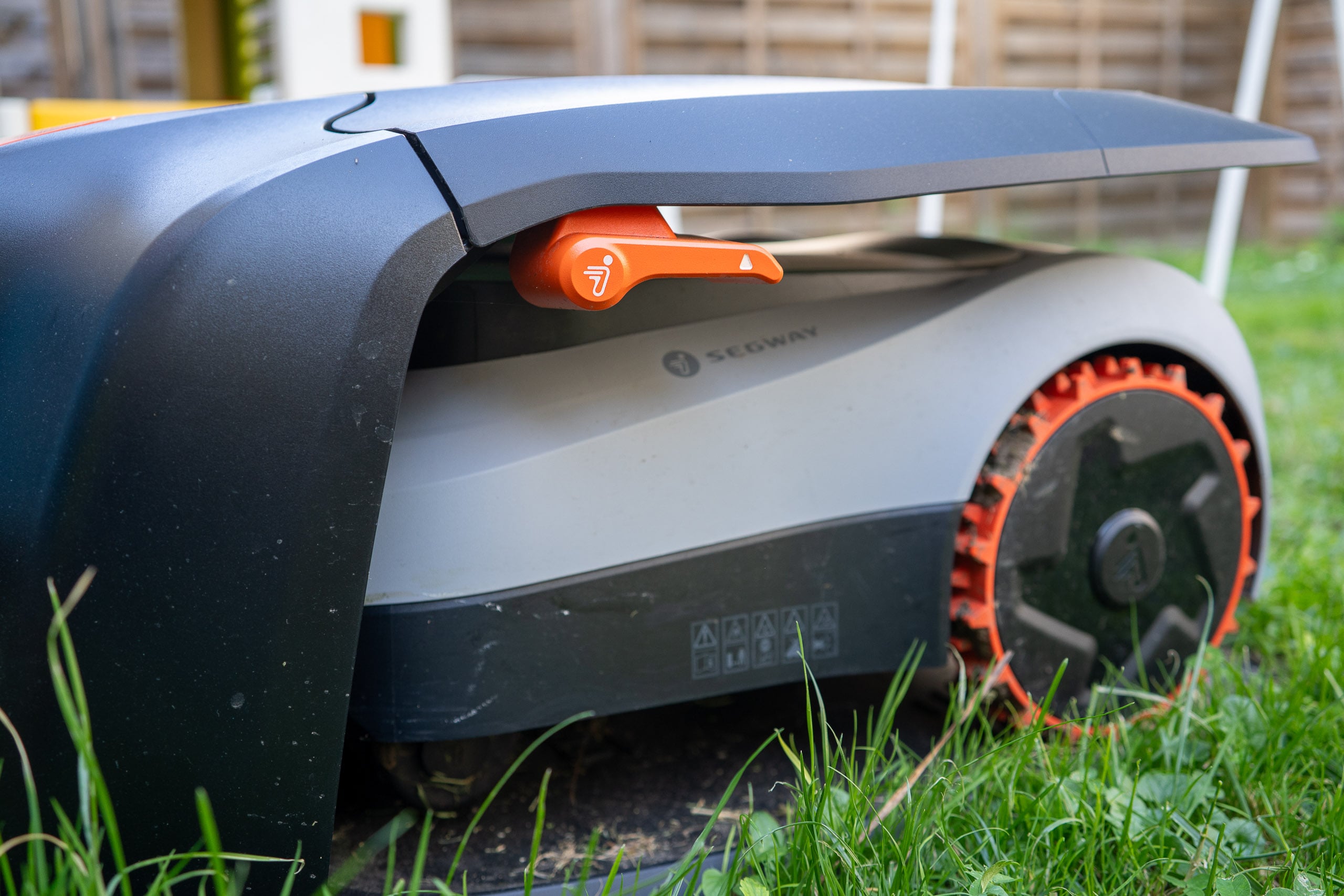 Mähroboter mit Arm: Sechs Hersteller lösen die Rasenkante, und der Igelschutz kostet extra Navimow von der Seite, das Gehäuse ragt über die Messerscheibe hinaus, daneben steht hohes Gras