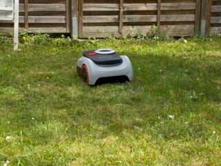 Navimow i208 im Reihenhausgarten, am Zaun bleibt ein Grasstreifen stehen. Genau das soll ein Mähroboter mit Arm lösen