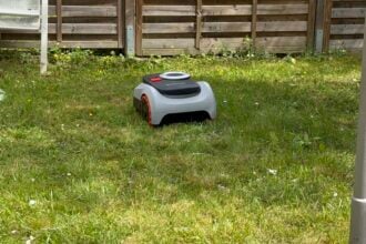 Navimow i208 im Reihenhausgarten, am Zaun bleibt ein Grasstreifen stehen. Genau das soll ein Mähroboter mit Arm lösen
