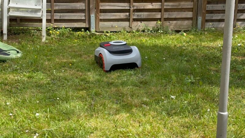 Navimow i208 im Reihenhausgarten, am Zaun bleibt ein Grasstreifen stehen. Genau das soll ein Mähroboter mit Arm lösen