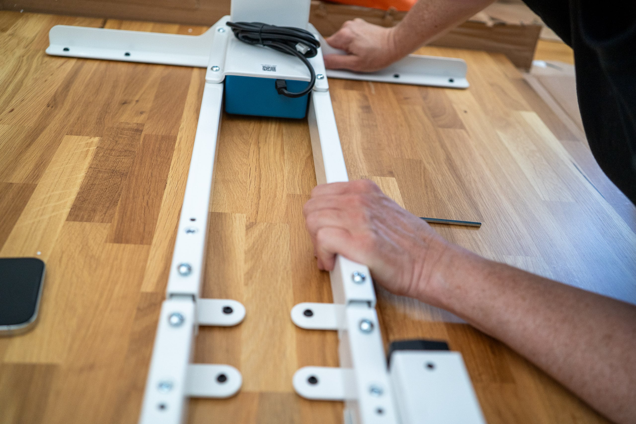 Neid am Arbeitsplatz: der Flexispot E200 im Test Verschrauben der Teleskop-Querstreben auf der Plattenunterseite