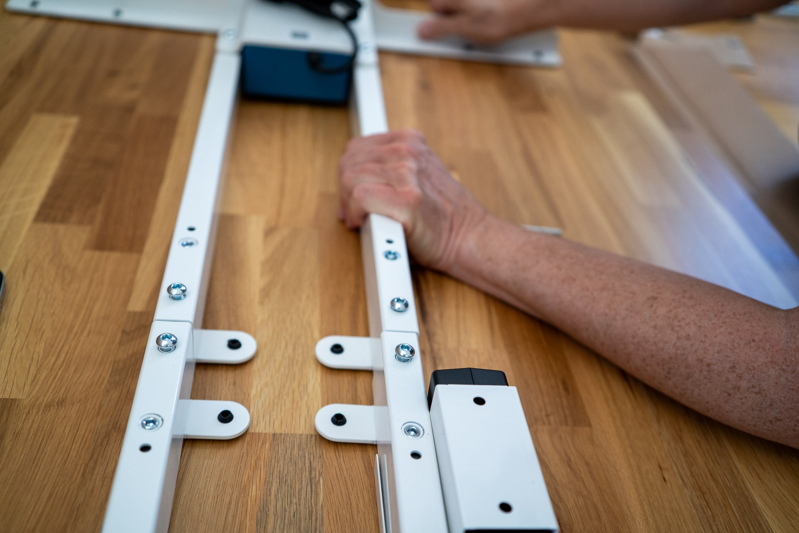 Neid am Arbeitsplatz: der Flexispot E200 im Test Handgriffe beim Ausrichten der Gestellschienen während des Aufbaus