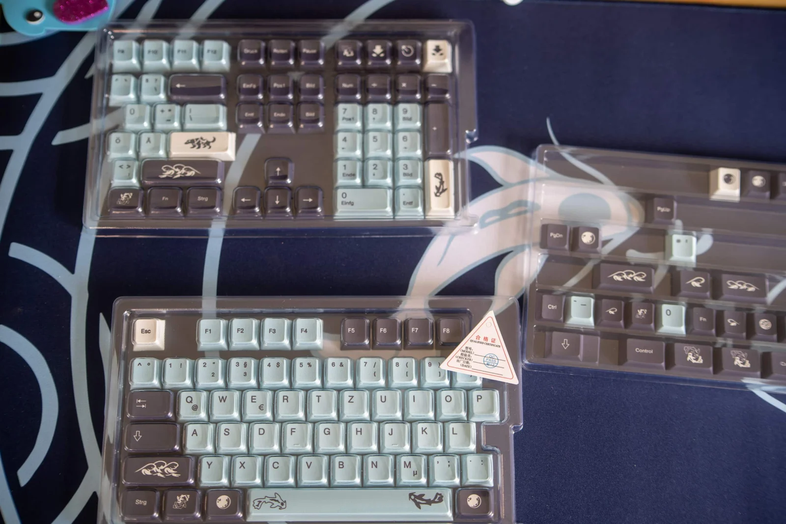 Keycaps-Klub: GMK Mizu Klon in ISO-DE – pragmatisch, nicht perfekt Schwarze und weiße Tastenkappen in Schutzhüllen, für mechanische Tastaturen, mit Tiermotiven und deutschen Beschriftungen.