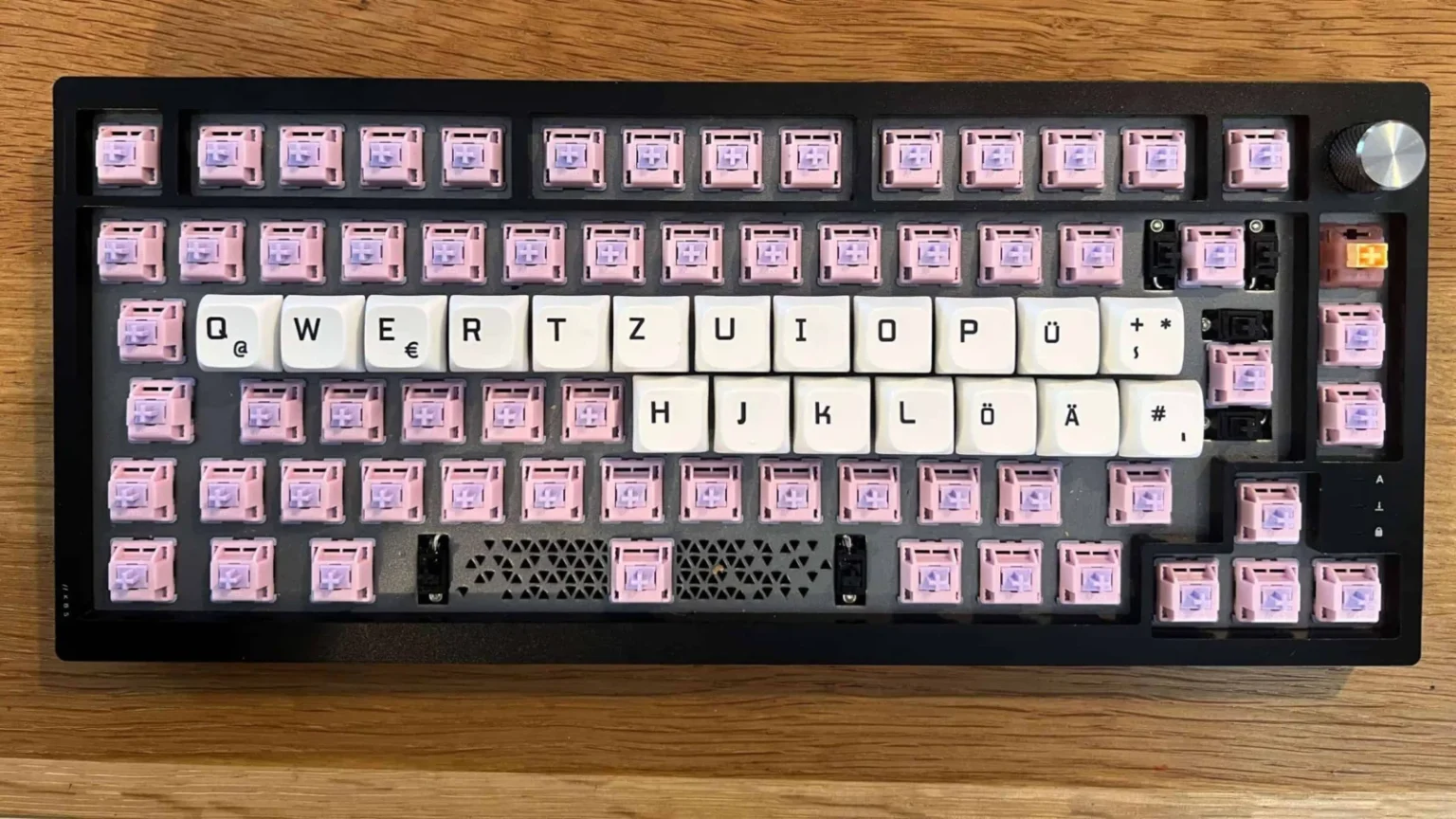 Edelstahl-Tastatur mit pinken Custom-Keycaps und weißen Tastenkappen in deutscher Layout.