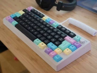 Bunte mechanische Tastatur mit Pastell-Keycaps auf Holzschreibtisch.