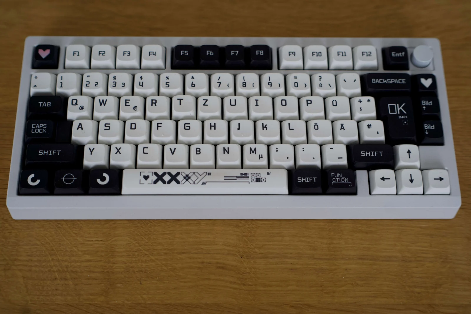 Zoom75 Review: Mein Keyboard-Trip zwischen Flexibilität und Thock Schwarz und weiße Tastatur mit dekorativen Keycap-Designs auf einem Holztisch.