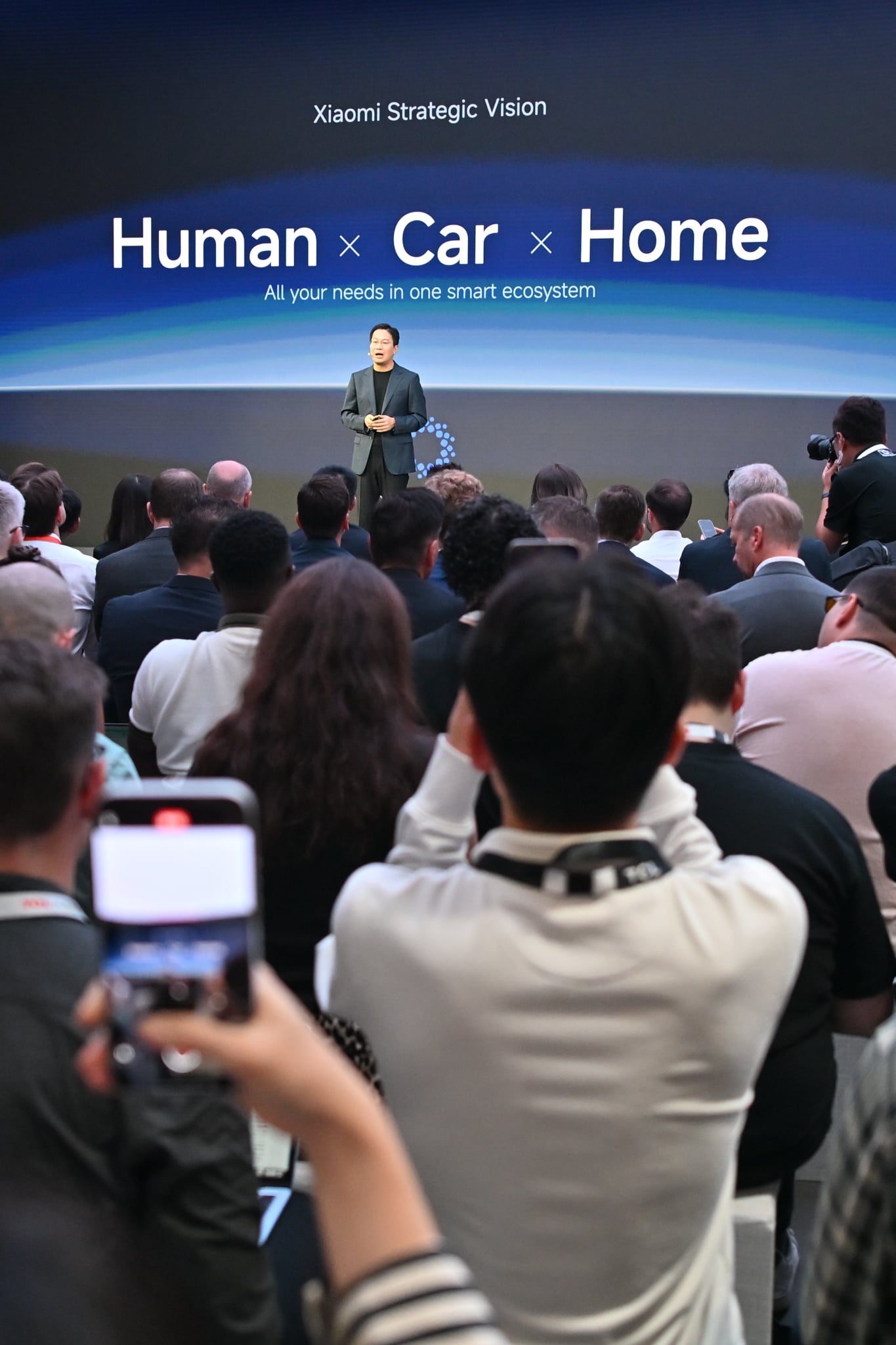 Xiaomi-Keynote auf der IFA 2026 mit der Folie Human, Car, Home, das Publikum filmt mit Handys