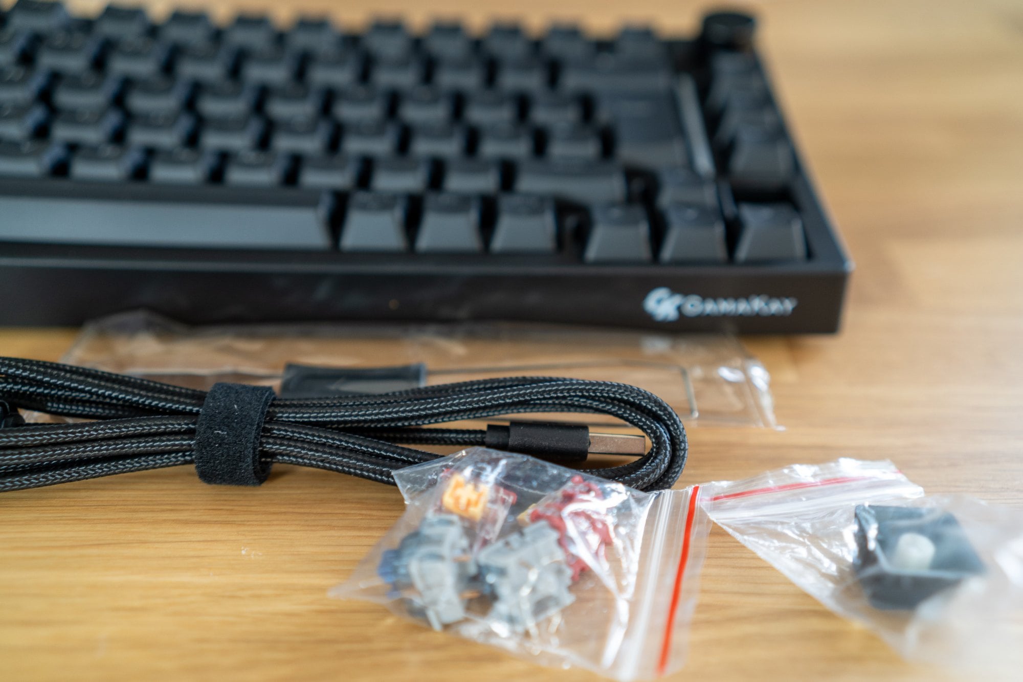 Nylonummanteltes USB-C-Kabel und zwei Tüten mit Ersatz-Switches vor der Gamakay TK75 TMR