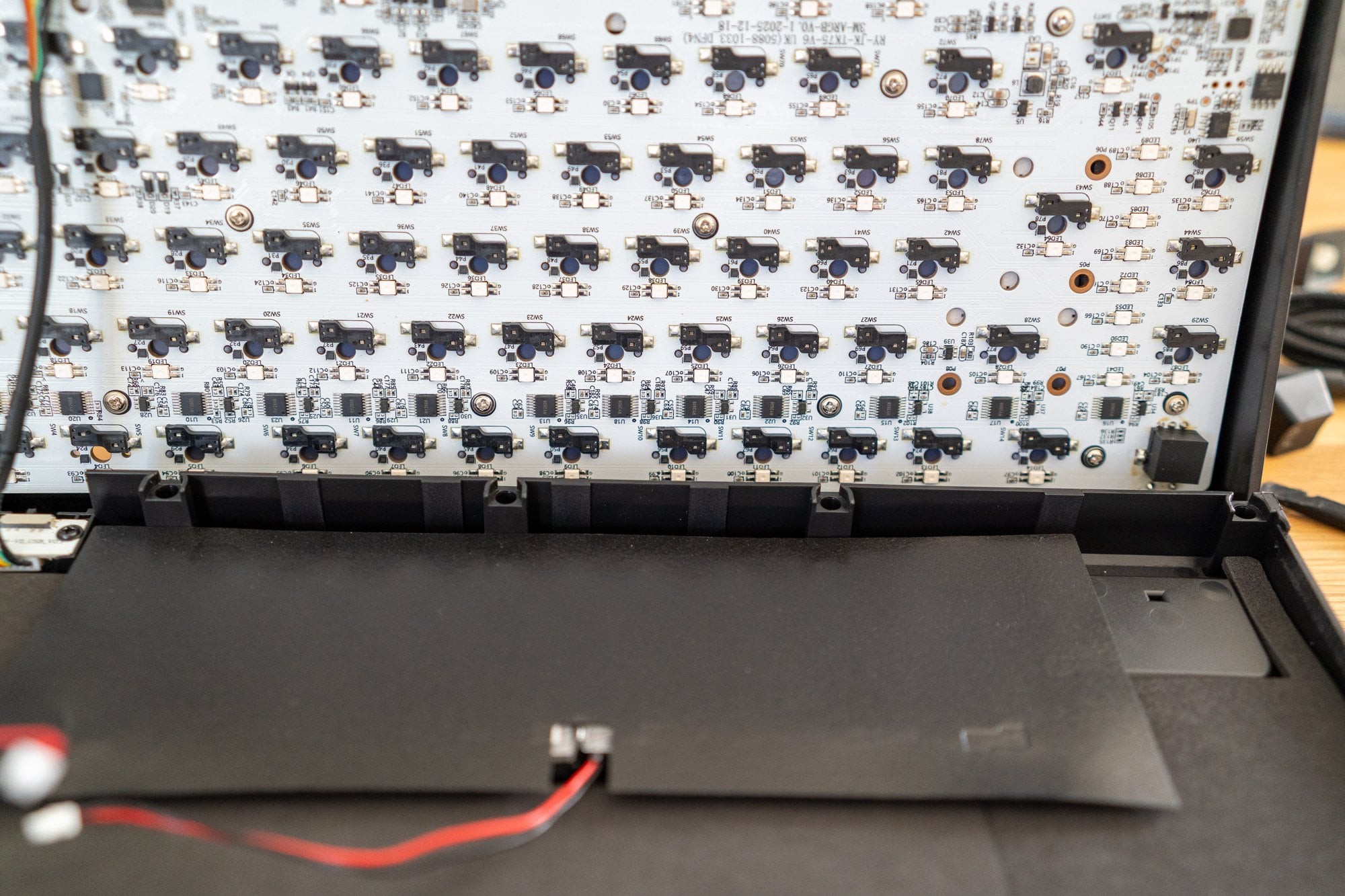 Geöffnete Gamakay TK75 TMR: Platine mit Hot-Swap-Sockeln, TMR-Sensoren und dem Aufdruck RY-JX-TK75-V6 (5088), darunter der Akku im Boden