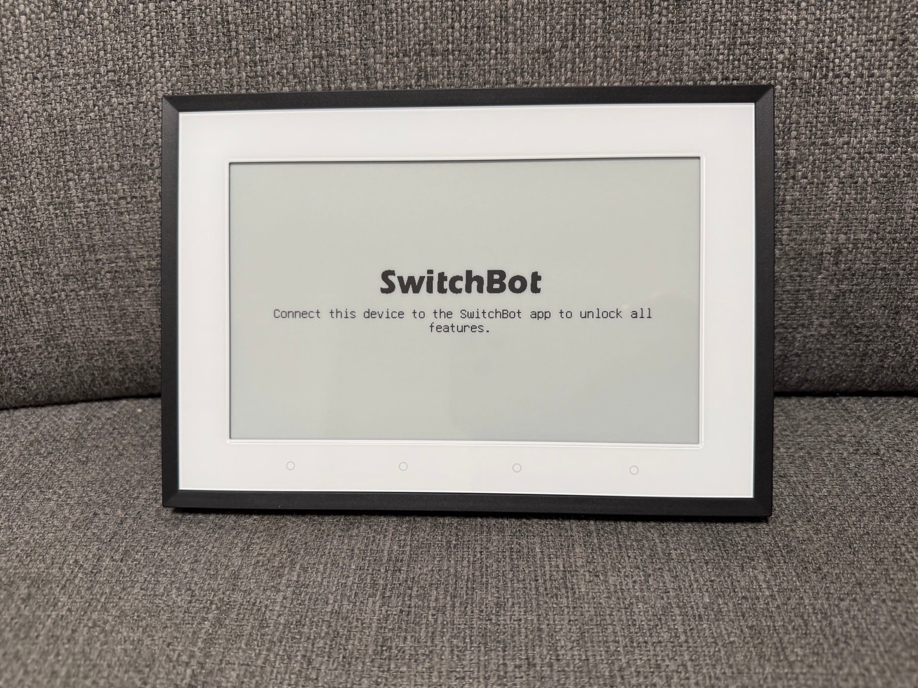 SwitchBot Wetterstation Test: Schönes E-Ink, winzige Schrift, zickige App SwitchBot Wetterstation Test: E-Ink-Display im schwarzen Rahmen mit Willkommenstext auf dem Sofa