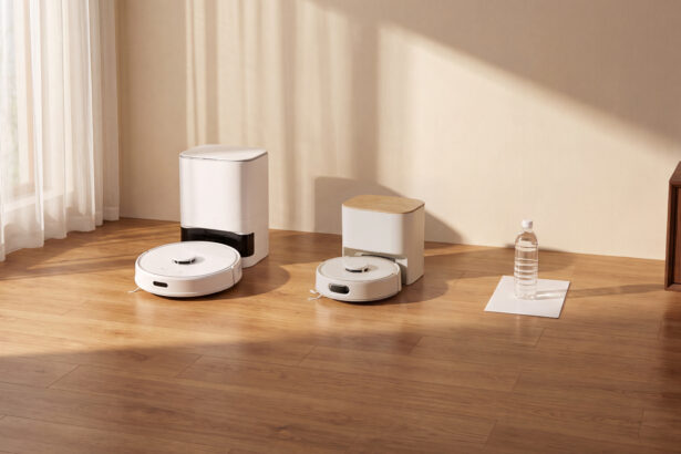 SwitchBot K11+ Pro mit kompakter Absaugstation neben einer größeren Station, daneben DIN-A4-Blatt und 500-ml-Flasche als Größenvergleich (Bild: SwitchBot)