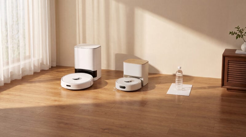 SwitchBot K11+ Pro mit kompakter Absaugstation neben einer größeren Station, daneben DIN-A4-Blatt und 500-ml-Flasche als Größenvergleich (Bild: SwitchBot)