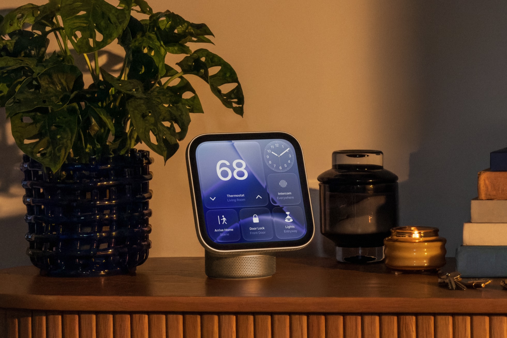 Apple HomeView steht auf einem Holz-Sideboard neben einer Zimmerpflanze, das Display zeigt Thermostat, Türschloss und Licht