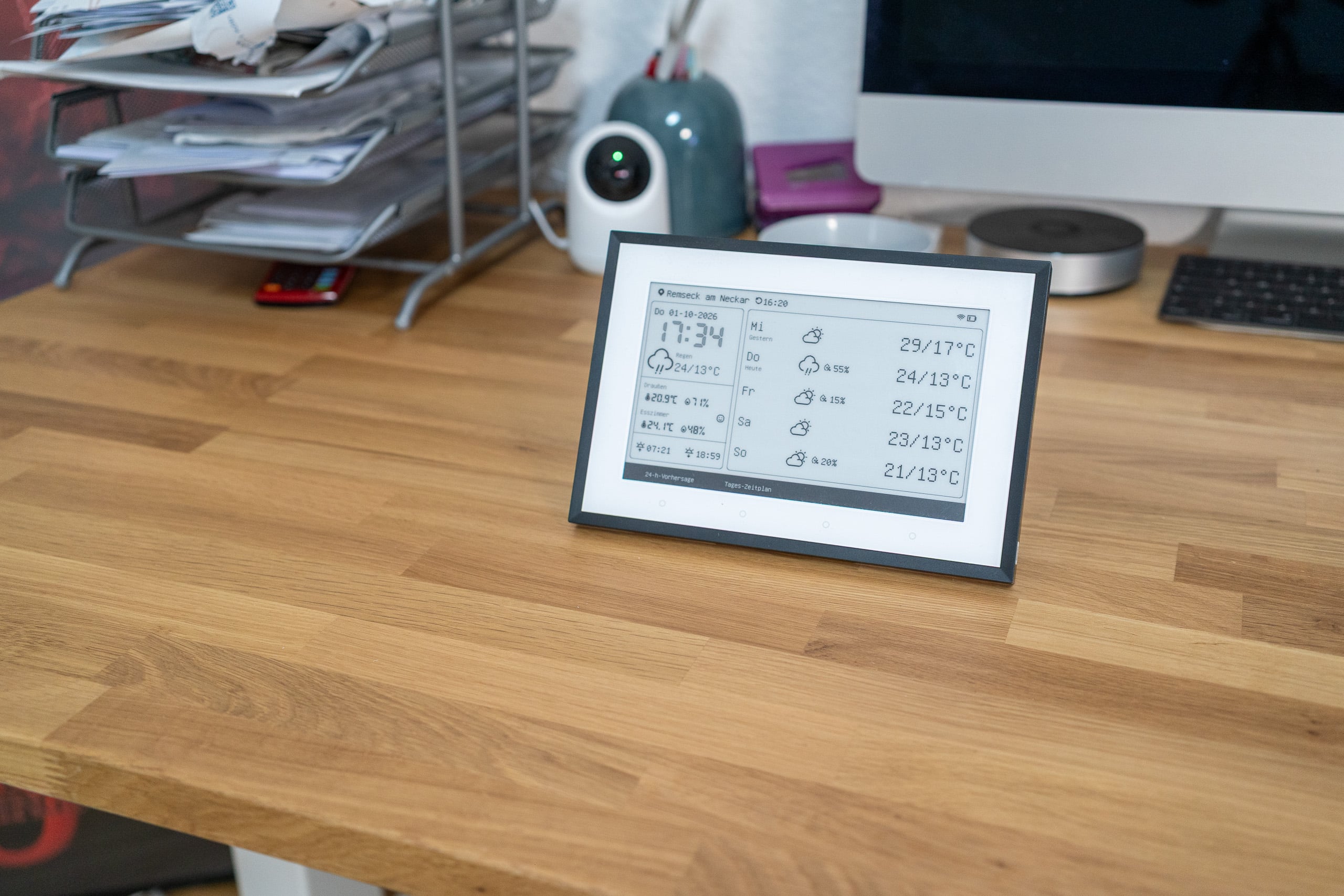 SwitchBot Wetterstation Test: Schönes E-Ink, winzige Schrift, zickige App SwitchBot Wetterstation auf einem Schreibtisch aus Eiche, im Hintergrund Ablagen und ein Monitor