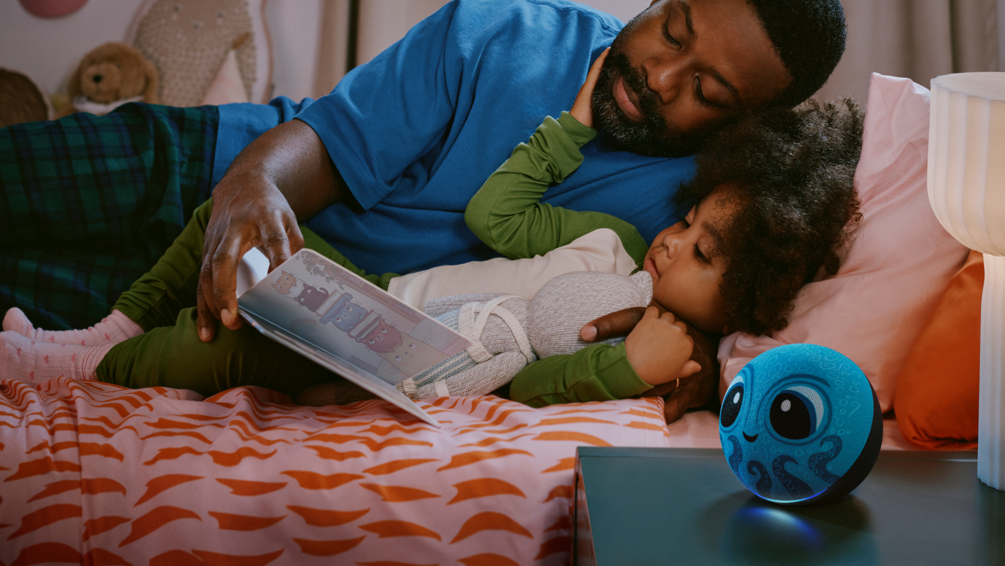 Amazon Kids Echo Dot 2026 im Kraken-Design auf dem Nachttisch, Vater liest Kind vor (Bild: Amazon)